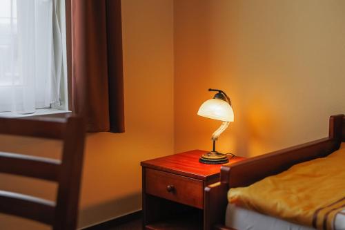 a lamp on a wooden table next to a bed at JazzPenzion in Čadca