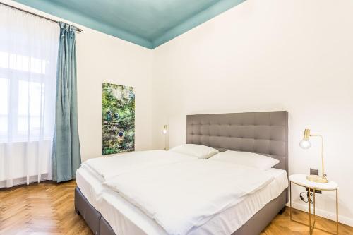 a white bedroom with a large bed and a window at Designer Boutique Apartments Graz Trauttmansdorffgasse in Graz