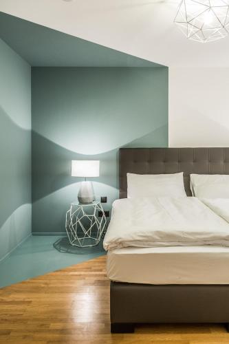 a bedroom with a bed with a blue accent wall at Designer Boutique Apartments Graz Trauttmansdorffgasse in Graz