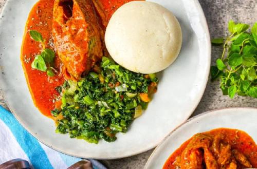 a white plate with a bowl of food and a bowl of sauce at Amazing Grace Hotel & Suites in Accra