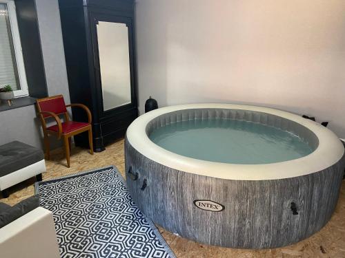a hot tub in a room with a red chair at Chambre L Arts de Vivre in Corcelles-les-Arts