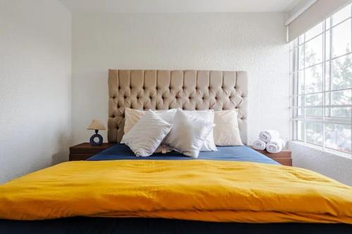 a bedroom with a large bed with a yellow blanket at Estadio GNP, Foro Sol, Autódromo Ciudad de México in Mexico City