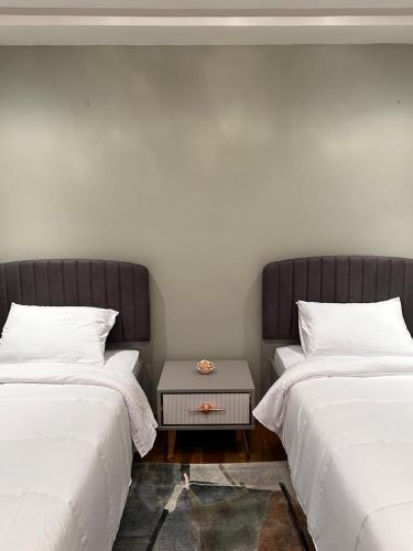 two beds with white sheets and a table between them at Sublime chalet à Ifrane avec piscine et parking gratuit in Ifrane