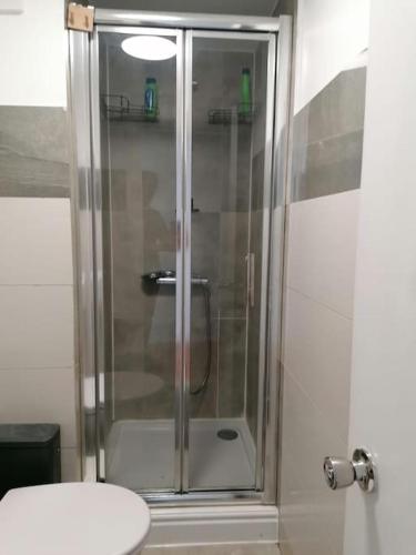 a shower with a glass door in a bathroom at King's Cross Road Private Rooms in London