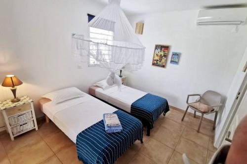 a room with two beds and a chair in it at Bungalow colombo résidence Ti-Figues in Saint-François