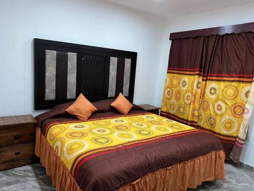 a bedroom with a bed with a yellow comforter at Departamento completamente nuevo y amueblado in Tonalá