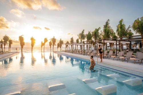 a woman and a child standing in a pool at a resort at Riu Palace Kukulkan - Adults Only - All Inclusive in Cancún