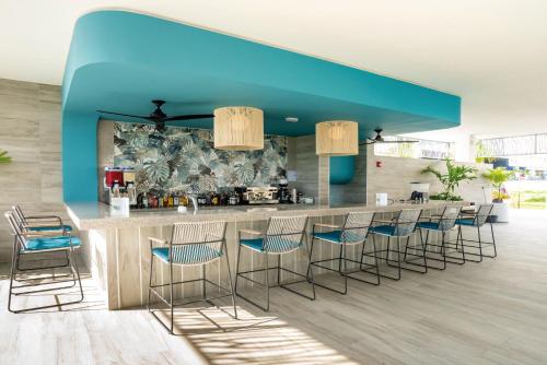 a lobby with a bar with blue ceilings and stools at Riu Palace Kukulkan - Adults Only - All Inclusive in Cancún
