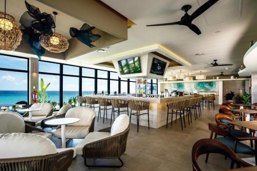 a restaurant with a bar with chairs and tables at Riu Palace Kukulkan - Adults Only - All Inclusive in Cancún