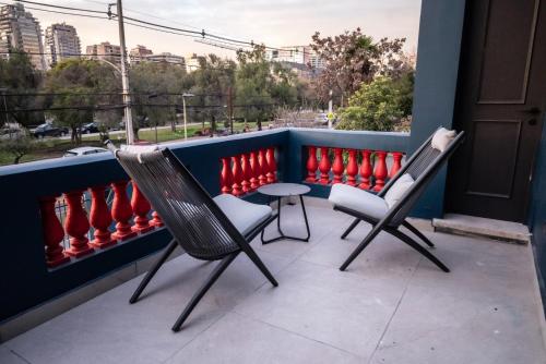 two chairs and a table on a balcony with red baseball bats at Casa Cecilia Santiago in Santiago