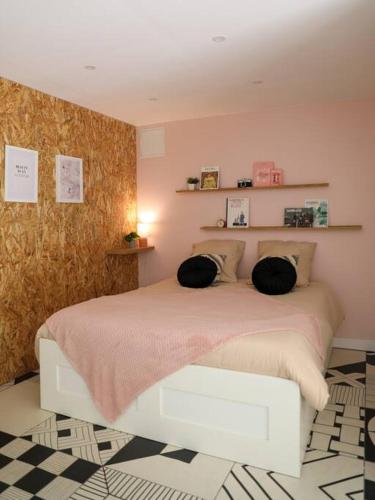 une chambre avec un lit avec deux oreillers dessus dans l'établissement Appartement rez-de-chaussée et patio, à Romans-sur-Isère