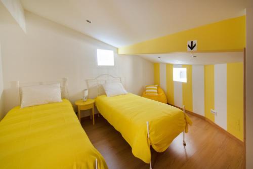two beds in a room with yellow sheets at Terraço da Vila in Ponte de Lima