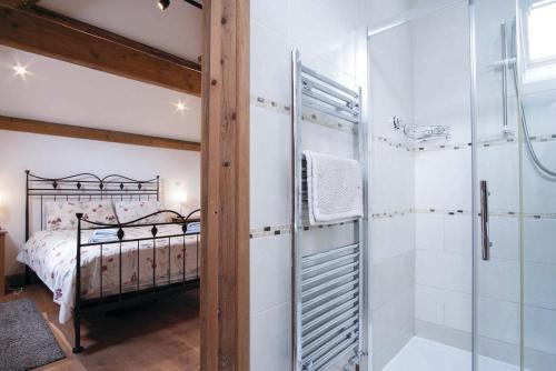 a bathroom with a shower and a bedroom with a bed at The Stables - 3 Bedroom Cottage - Beavers Hill in Manorbier