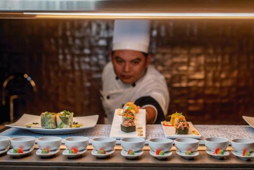 a chef behind a table with dishes of food at Riu Palace Kukulkan - Adults Only - All Inclusive in Cancún