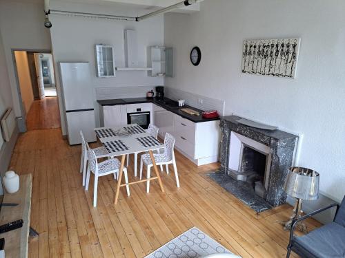 une cuisine avec une table et des chaises ainsi qu'une cheminée dans l'établissement Lons centre T1 rue du commerce, à Lons-le-Saunier