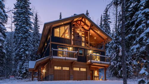 a large wooden house in the woods in the snow at Lush Mountain Accommodations in Golden