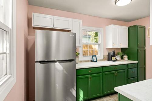a kitchen with green cabinets and a stainless steel refrigerator at Art Deco Oasis A Stylish Retreat in Peoria Heights