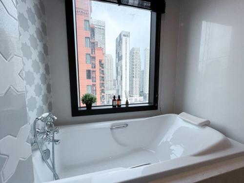 a white bath tub in a bathroom with a window at Expansive Luxury 2BR - Ultra Fast Wifi - Phrom Phong in Bangkok