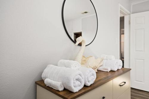 a bathroom with towels on a dresser with a mirror at The Modern Elm Escape a cozy 2bd in the Heights in Peoria Heights