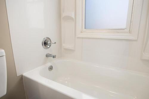 a white bath tub in a bathroom with a window at The Modern Elm Escape a cozy 2bd in the Heights in Peoria Heights