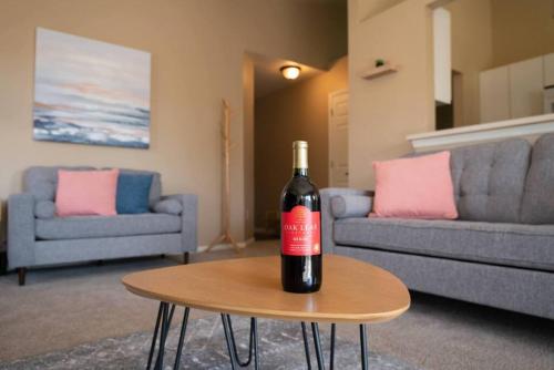 a bottle of wine sitting on a table in a living room at GRAUHAUS Tasteful 3BD with KING bed in Pekin in Pekin