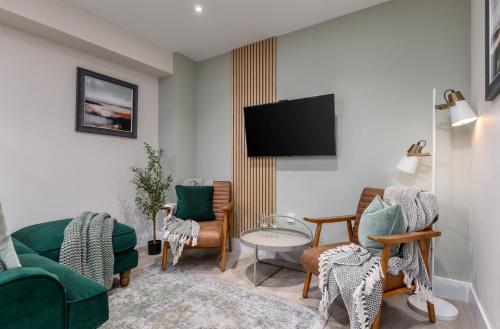a living room with chairs and a flat screen tv at Central Stirling City Escape in Stirling
