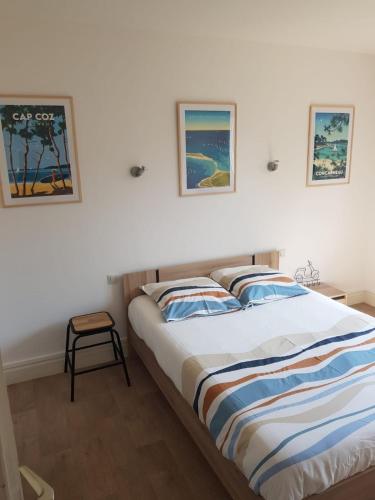 une chambre avec deux lits et deux tableaux au mur dans l'établissement Le Transat, à 5 min de la superbe plage du Cap-Coz à Fouesnant, proche des commerces, à Fouesnant