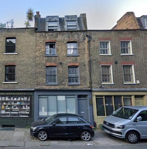 two cars parked in front of a brick building at King's Cross Road Private Rooms in London