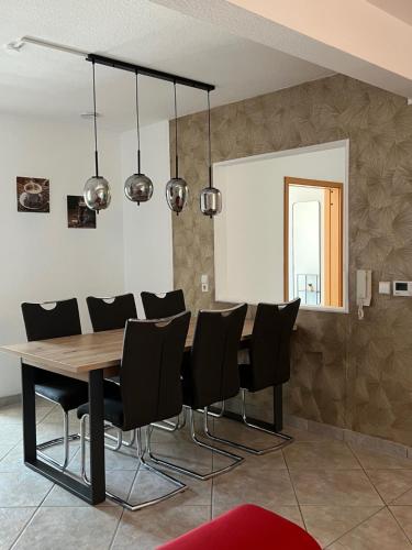 a dining room with a wooden table and black chairs at Apartment Sandperle nahe A5 und EUROPAPARK in Willstätt