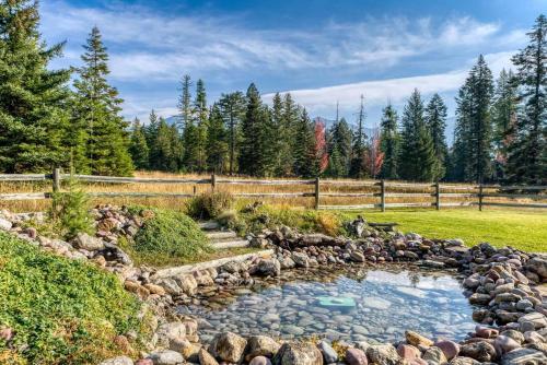 a pond in a yard with rocks and a fence at Montana Mountain Getaway in Creston