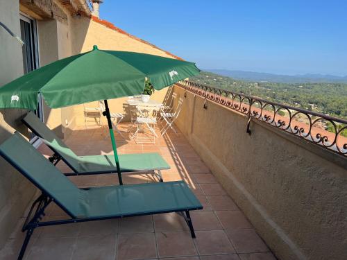 a pair of chairs and an umbrella on a balcony at Au cœur de Seillans, charmant logement, grande terrasse et panorama in Seillans