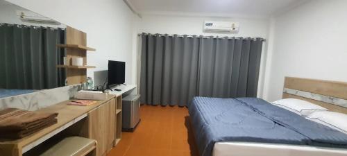 a bedroom with a bed and a desk with a television at Ratanasiri Hotel in Chaiyaphum