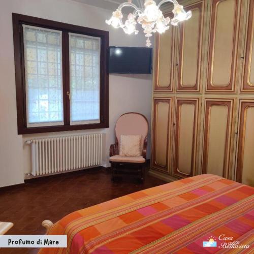 a bedroom with a bed and a chair and a chandelier at Casa Bellavista in Bergeggi