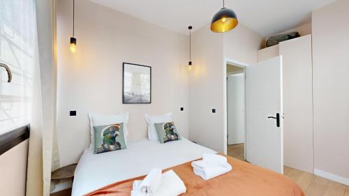 - une chambre avec un grand lit aux murs blancs dans l'établissement Bluestay 57 - Charmant appartement à Paris, à Paris