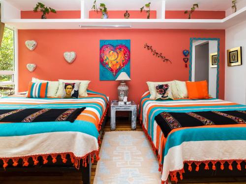 two beds in a room with orange walls at Casa Itzae B&B Polanquito Dog Friendly in Mexico City