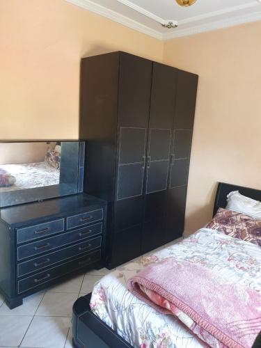 a bedroom with a large black dresser and a bed at Cité 9juillet C1 n7 in Mohammedia