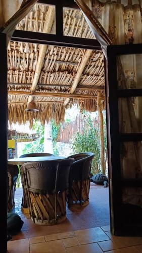 a table and chairs under a thatch roof at La casa de piedra y colores en Chichén Itzá in Chichén-Itzá