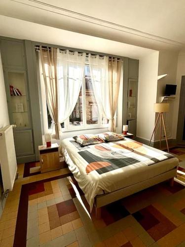 a bedroom with a large bed with a window at Le Magaline in Sainte-Savine