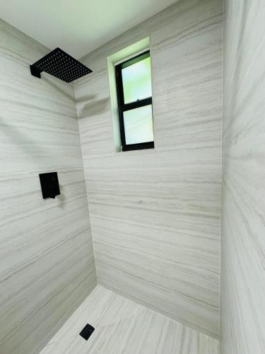 a bathroom with a window and a white wall at La Casita in Miami