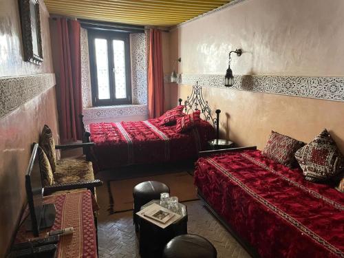 a room with two beds and a couch and a window at Riad Fes Baraka & SPA in Fès