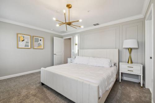 a white bedroom with a white bed and a chandelier at Storey Lake - Private Pool King Bed 4BD/3BA in Kissimmee