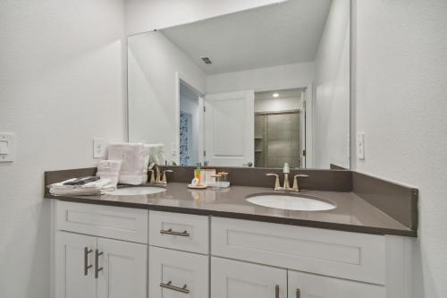 a bathroom with a sink and a large mirror at Storey Lake - Private Pool King Bed 4BD/3BA in Kissimmee
