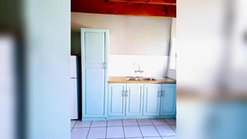 a kitchen with blue cabinets and a sink at Mond Kleine Guest House in Kleinmond
