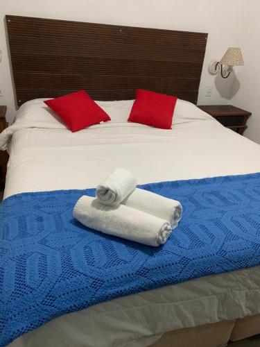 a bed with two towels and two red pillows at Vicentina Hospedagem in Tiradentes