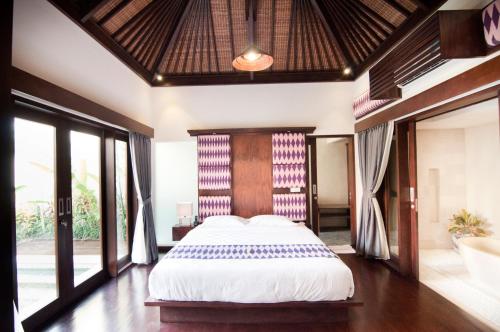 a bedroom with a large bed and a bath tub at Villa Puspa in Tanah Lot