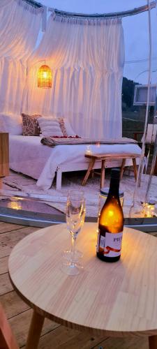 a bottle of beer and a wine glass on a table at The Hunter Valley Star Gazing BubbleHotel in Mulbring