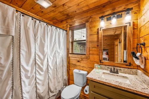 une salle de bain avec toilettes, lavabo et miroir dans l'établissement New 2BR with Loft Cabin by Parkway, Gatlinburg & GSMNP, à Sevierville