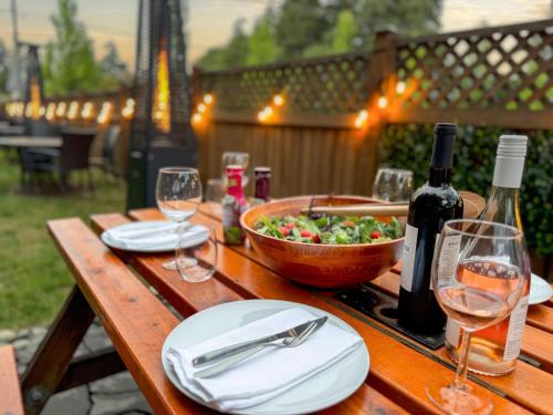 a wooden table with a bowl of salad and wine glasses at Coast Parksville Hotel in Parksville