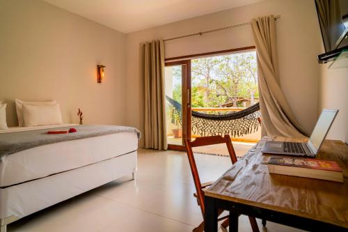 a bedroom with a bed and a laptop on a table at Casa Suiça Brasileira in Jericoacoara