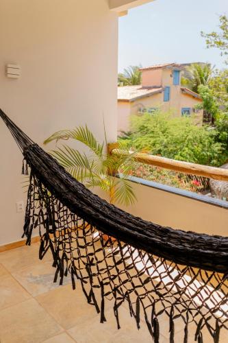 a hammock on a balcony with a palm tree at Casa Suiça Brasileira in Jericoacoara